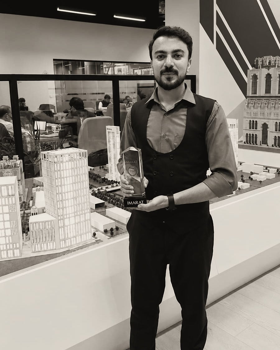 Zeeshan Saleem holding an IMARAT award in front of architectural scale models